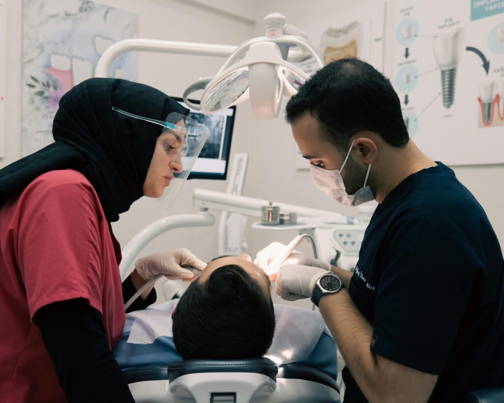Dentist and assistant examining a patient's teeth in a dental office.