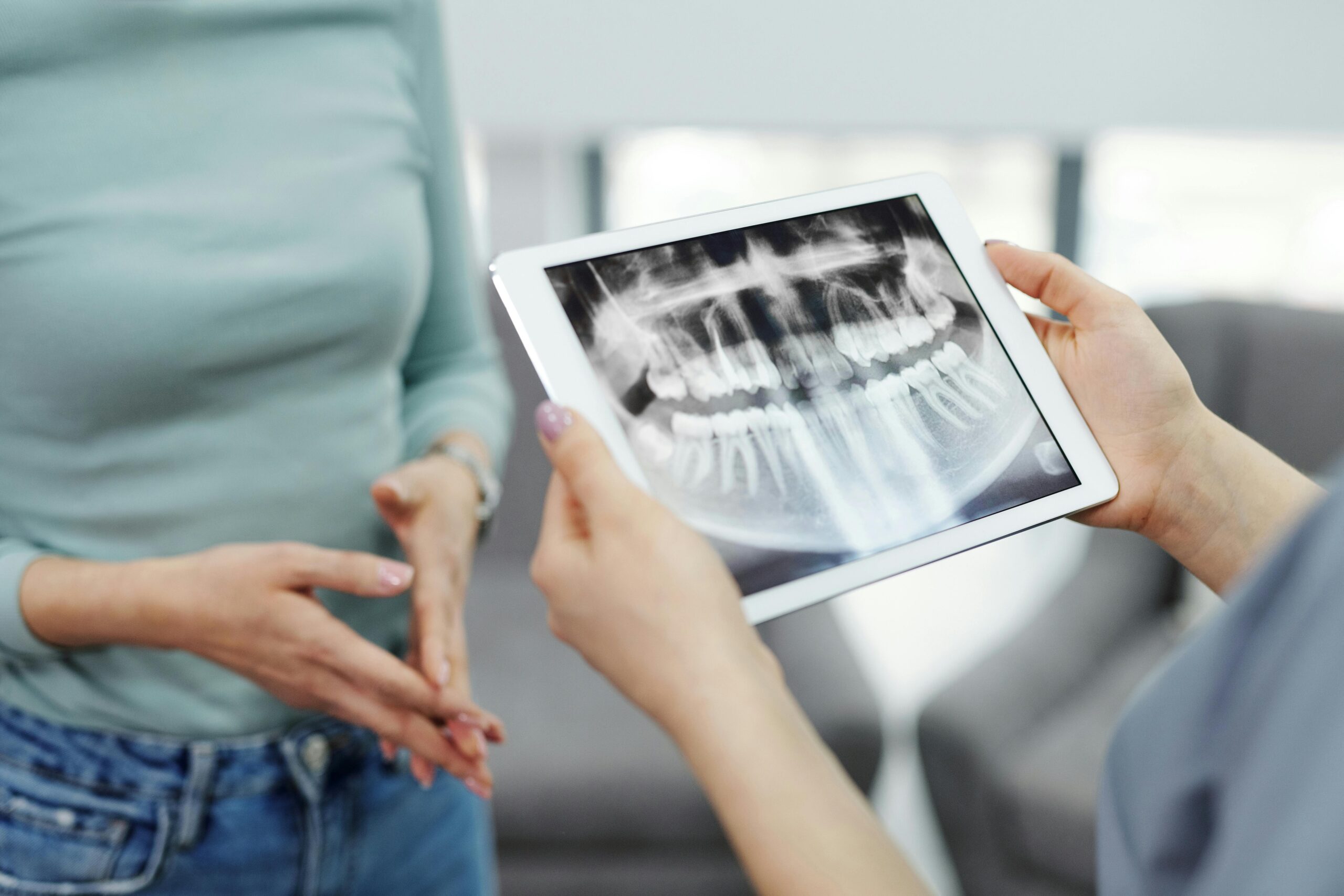 Dentist showing a dental X-ray on a tablet to a patient.