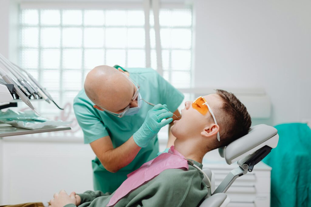Dentist examining a patient's mouth in a dental chair.
