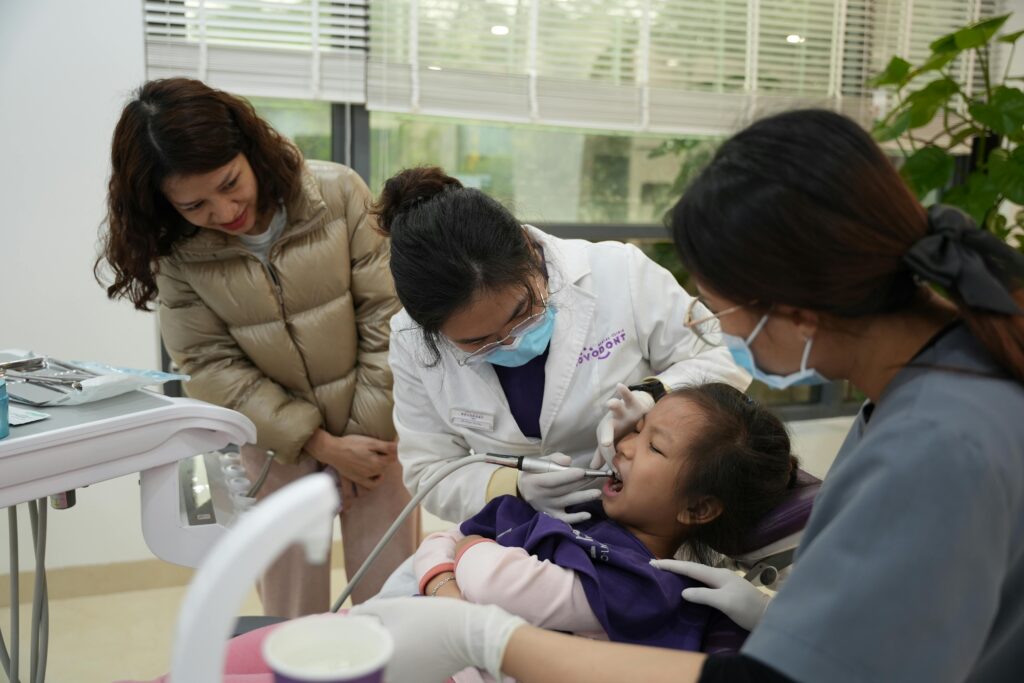 Dentist examining a child's teeth with a parent nearby.