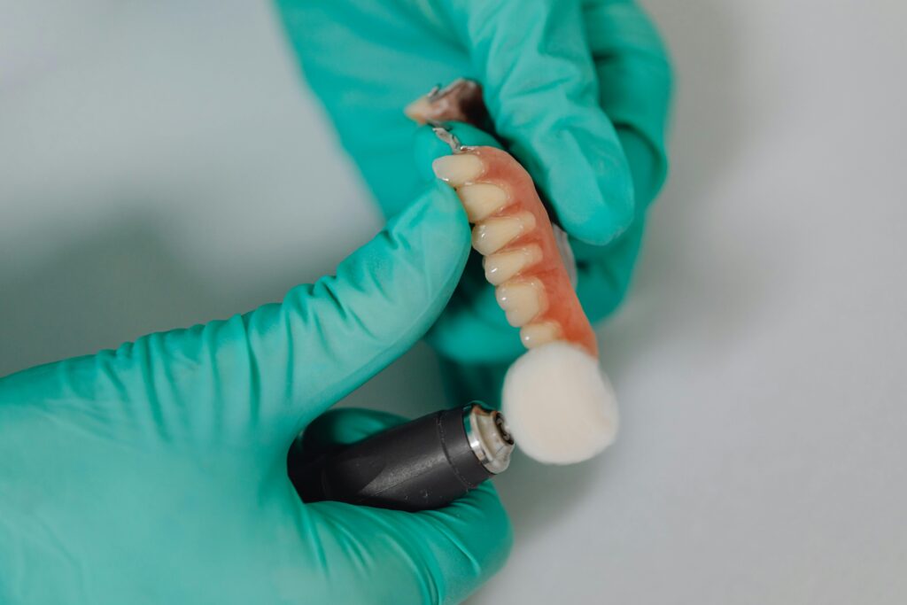 Gloved hands holding a dental prosthetic device.