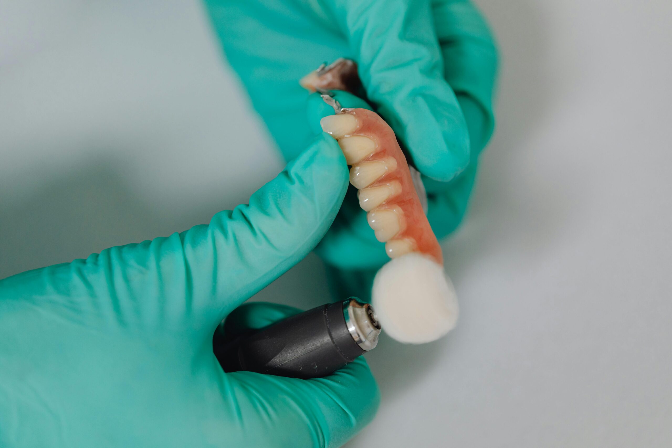 Gloved hands holding a dental prosthetic device.