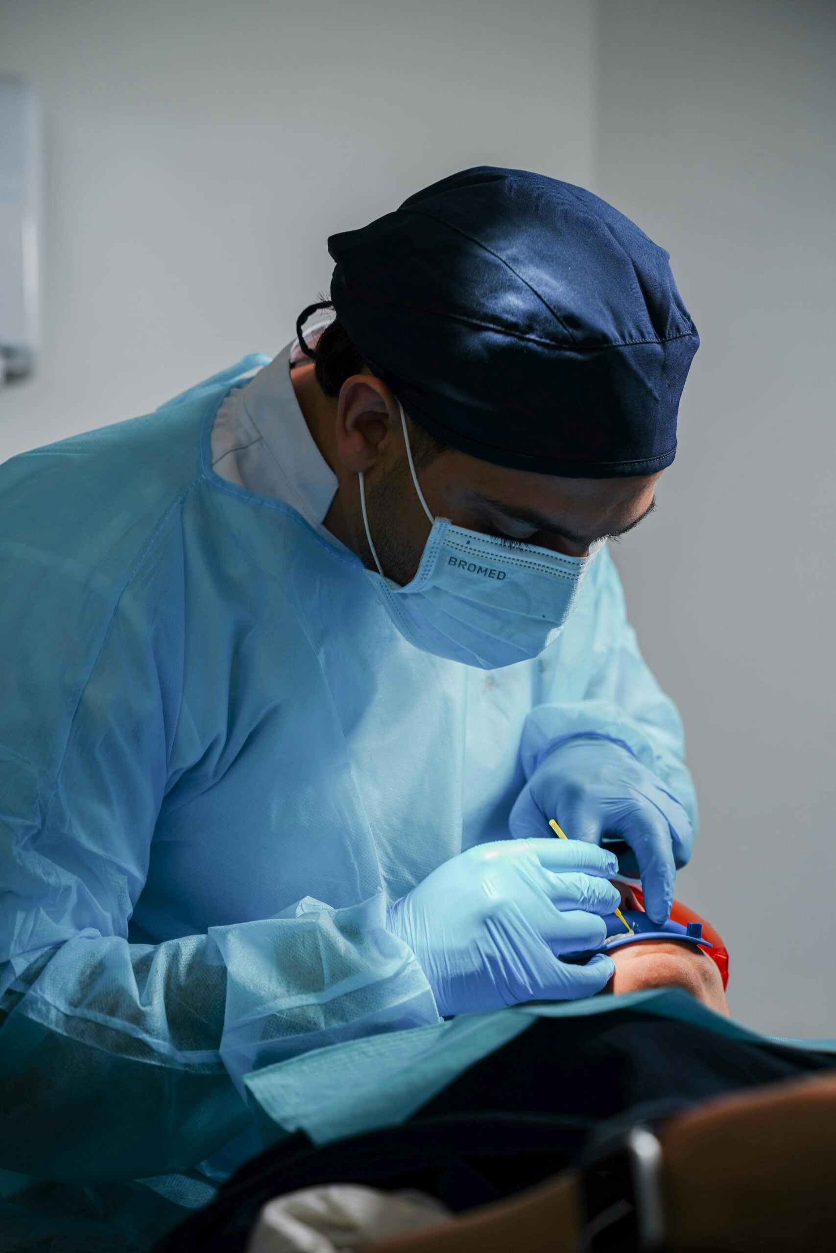 Dentist in blue scrubs performing a procedure on a patient.