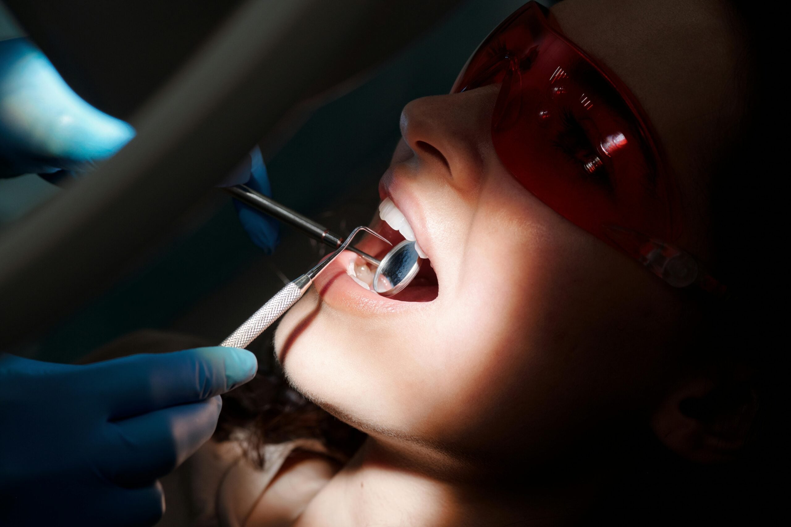 Dentist examining a patient's mouth with dental tools.