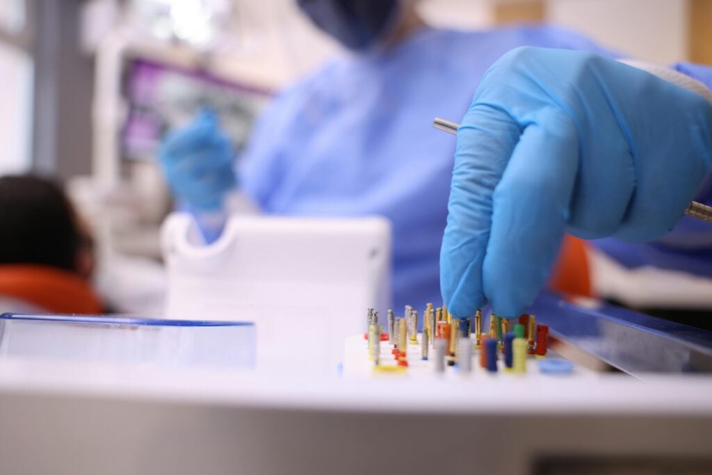 Dentist with gloved hands selecting dental tools in a clinic.