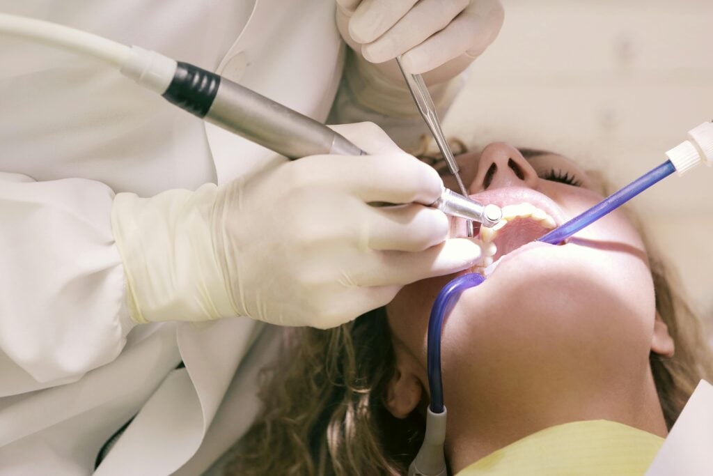 Dentist using tools in a patient's mouth during a procedure.
