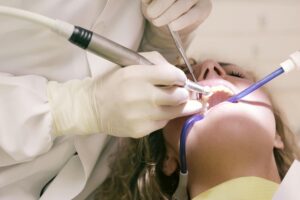 Dentist using tools in a patient's mouth during a procedure.